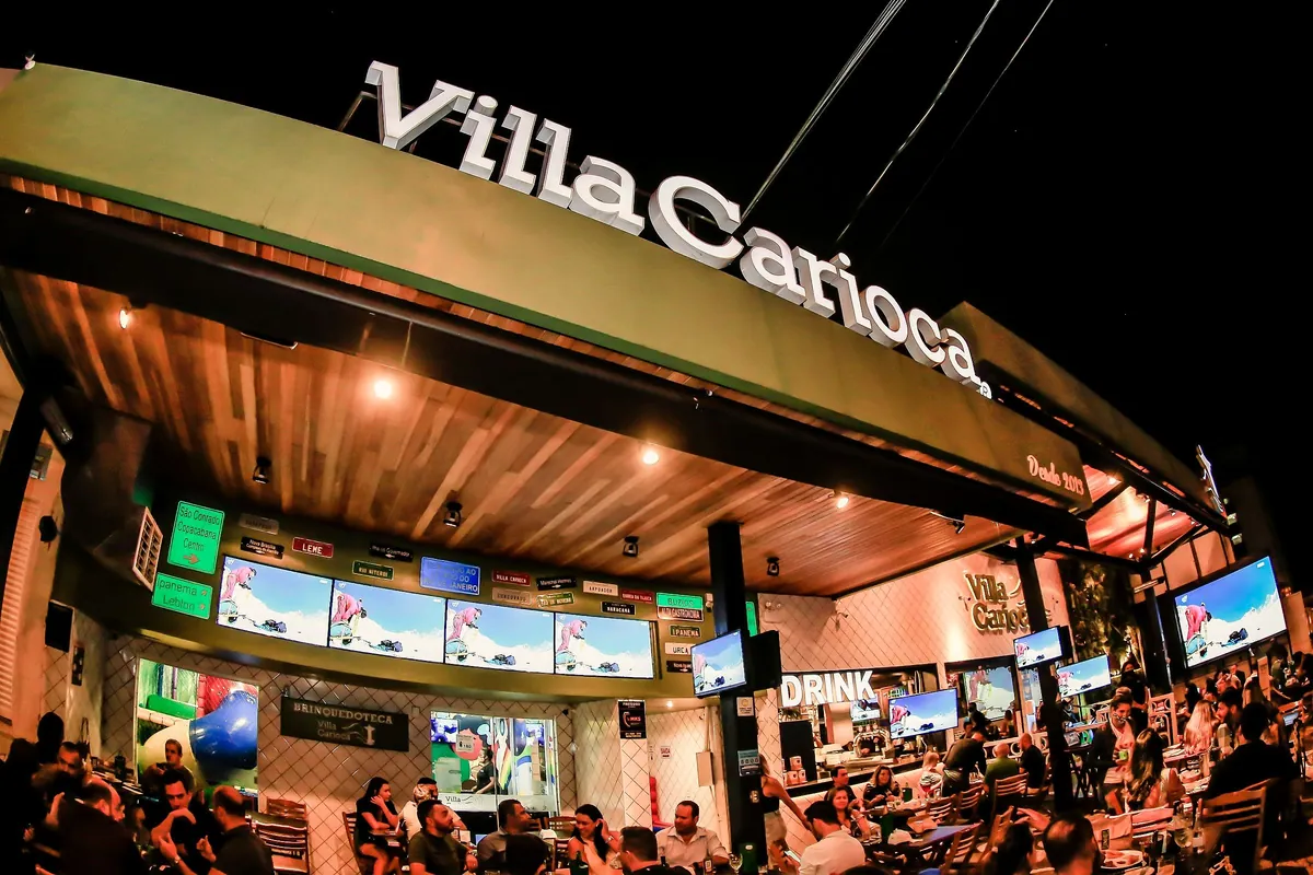 Fachada do Villa Carioca à noite, com o letreiro aceso, telões e a varanda cheia