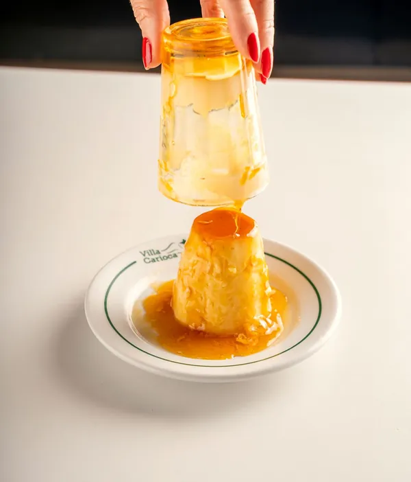 Pudim de leite sendo desenformado com calda de caramelo